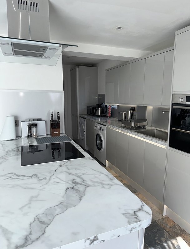 Modern kitchen with marble countertops, white cabinets, stainless steel appliances and island