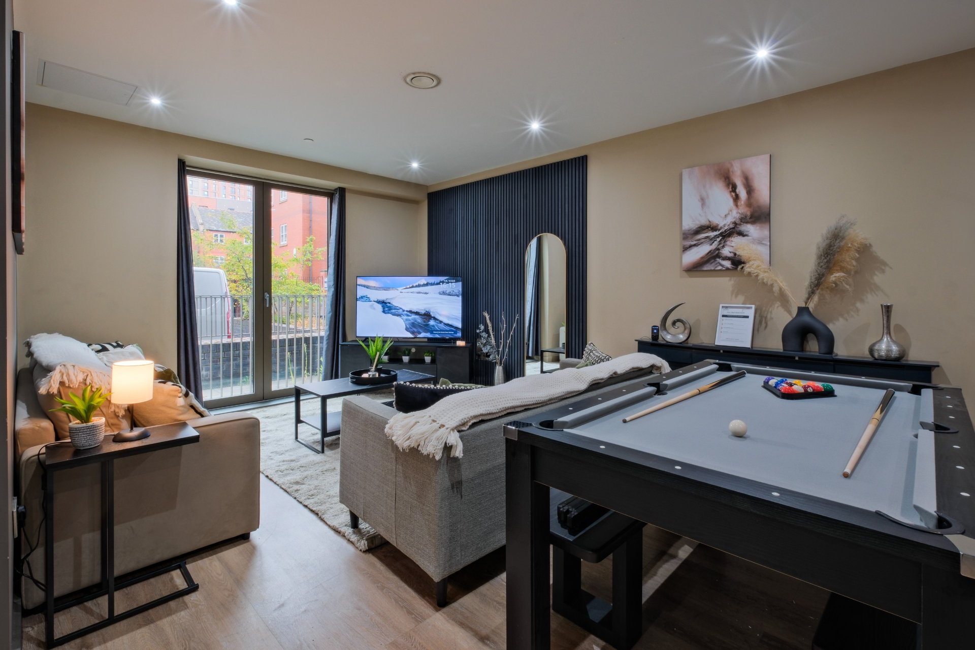 Modern living room with pool table, sofa, TV, and access to outdoor balcony