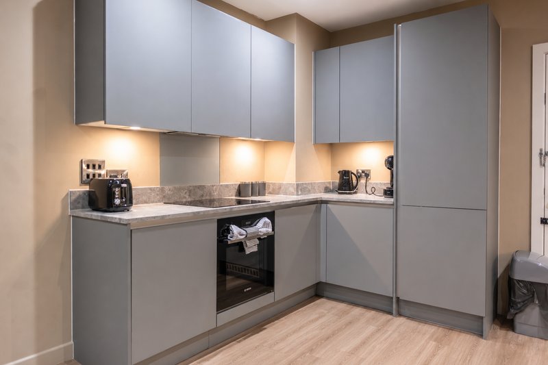 Modern kitchen with gray cabinetry, white countertop, built-in appliances and under-cabinet lighting