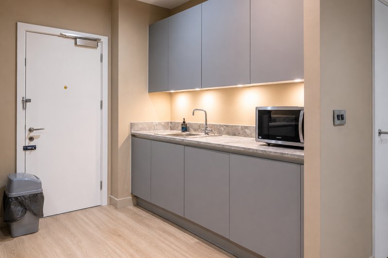 Modern kitchenette with gray cabinetry, marble countertop, microwave and sink