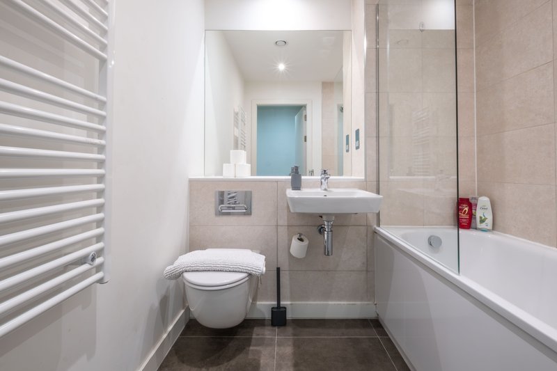 Modern bathroom with toilet, sink, mirror, bathtub and heated towel rail