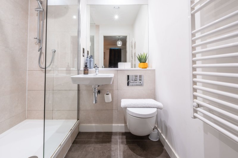 Modern bathroom with walk-in shower, white sink, toilet, and heated towel rail