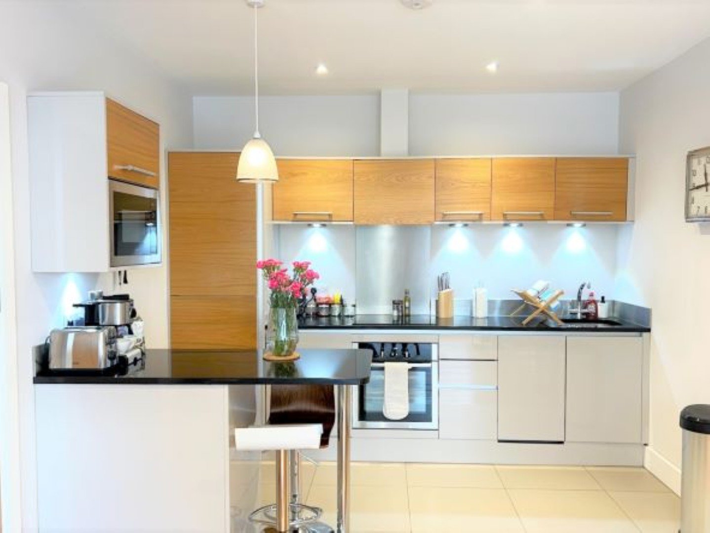 Modern kitchen with wooden cabinets, white countertops, stainless steel appliances and pendant lighting