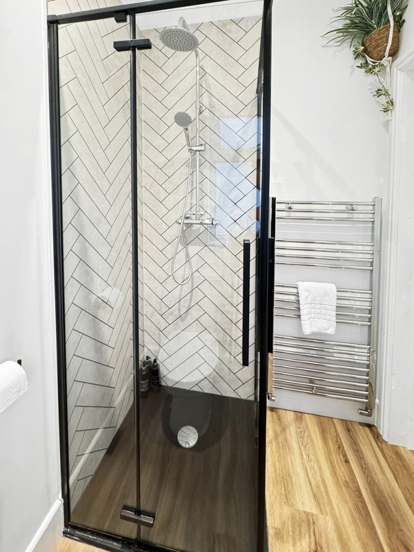 Modern bathroom with enclosed shower cubicle, herringbone tile, heated towel rail, and wooden flooring