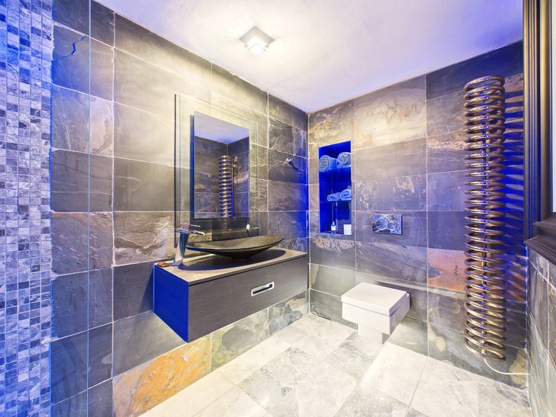 Modern bathroom with blue tile walls, floating vanity, mirror, shower enclosure and heated towel rail