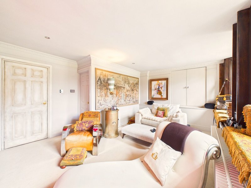 Bright bedroom with two single beds, upholstered seating, framed artwork and wooden furniture