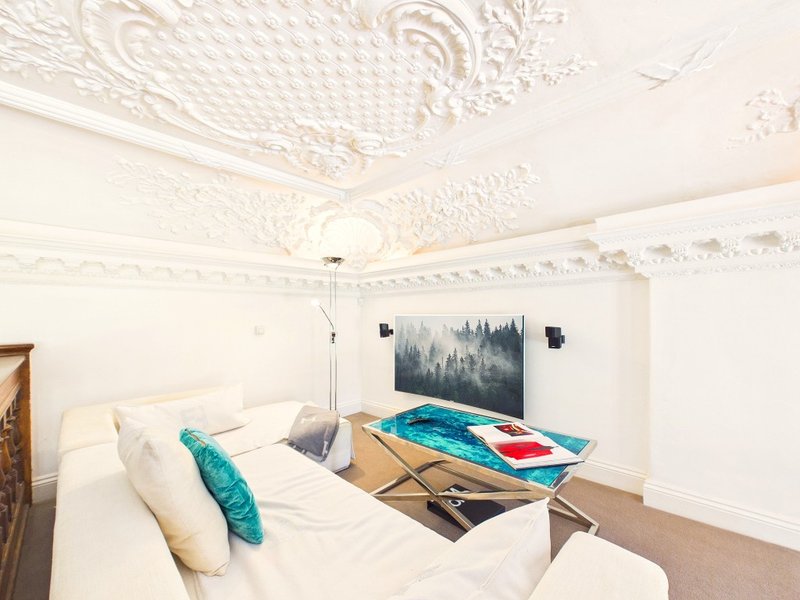 Bedroom with ornate ceiling, double bed, turquoise cushion, and forest artwork on wall
