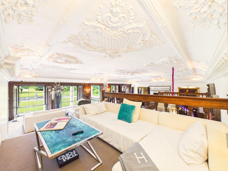 Bright attic living room with cream sofa, ornate ceiling detail, bookshelves and garden views