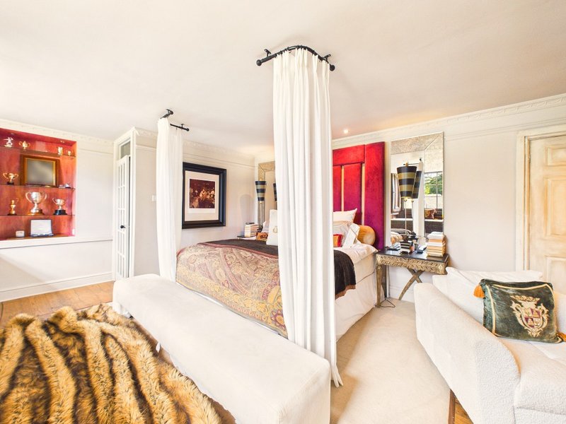 Spacious master bedroom with four-poster bed, red accent walls, and contemporary furnishings