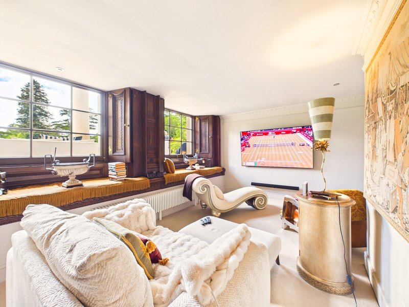Bright modern bedroom with bed, seating area by windows, TV, and wooden furnishings