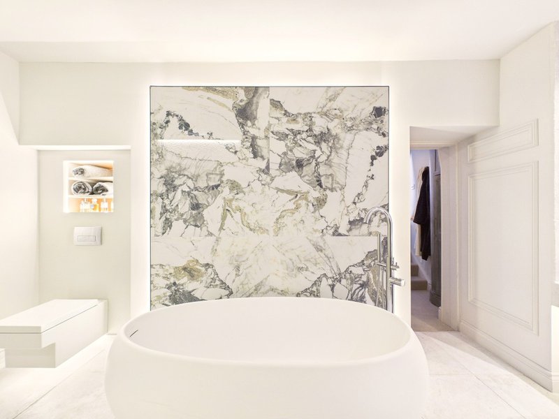 Modern bathroom with freestanding oval bathtub and marble feature wall