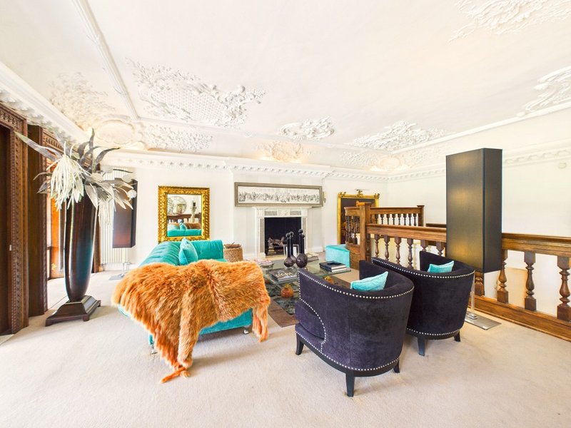 Spacious bedroom with bed, armchairs, fireplace and ornamental furnishings