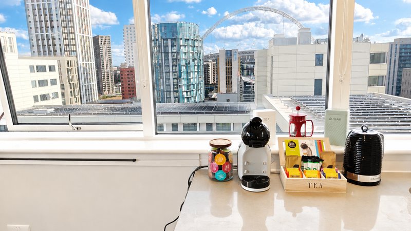 High-rise apartment windowsill with kitchen appliances and cityscape view through large windows