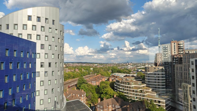 Cityscape view from high-rise apartment showing residential buildings, green spaces and sky