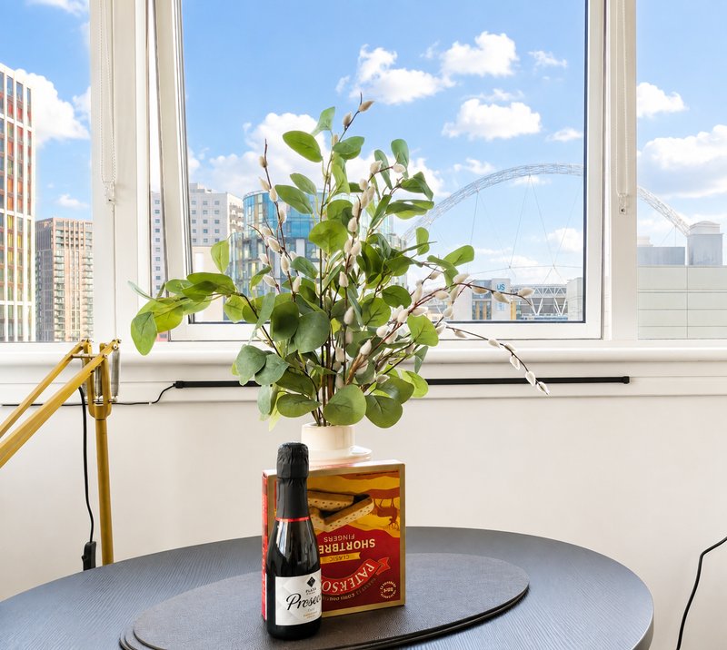 Round table with potted plant, wine bottle, and decorative box near large window overlooking city skyline