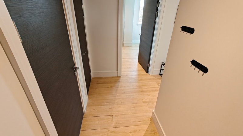 Hallway with multiple doors, wooden flooring, and cream-colored walls