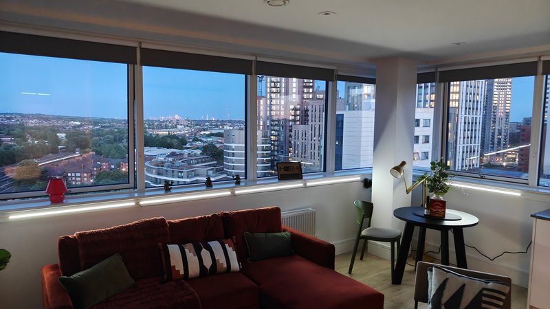 Modern living room with burgundy sofa, floor-to-ceiling windows overlooking city skyline