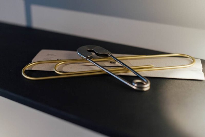 Close-up of safety pins and paper clips arranged on dark surface