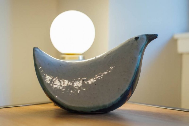 Modern sculptural table lamp with curved dark base and white globe light