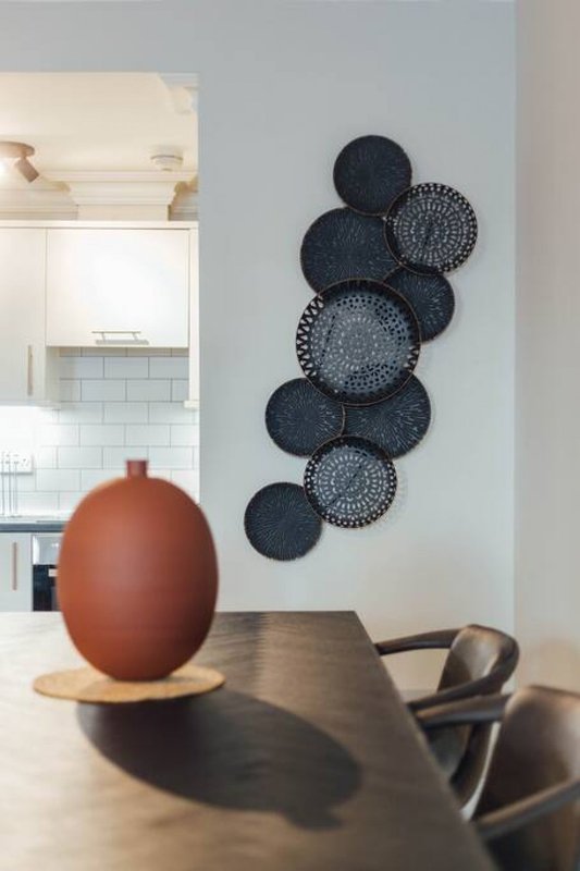 Open-plan kitchen and dining area with decorative wall plates and terracotta vase on table