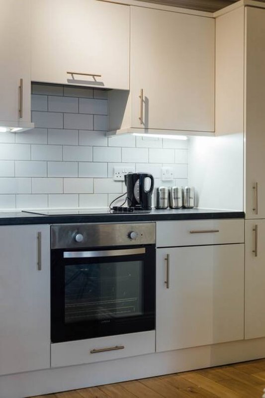 Modern kitchen with white cabinets, subway tile backsplash, built-in oven and kettle