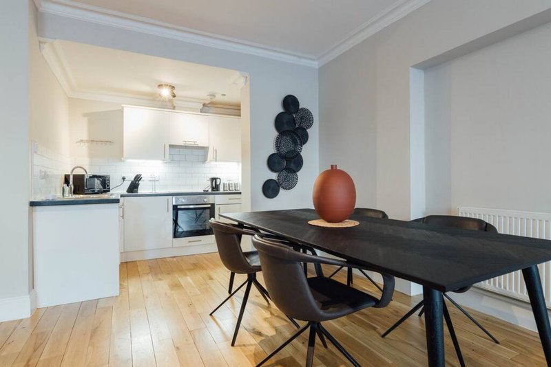 Open-plan kitchen and dining area with black table, chairs, and modern decor