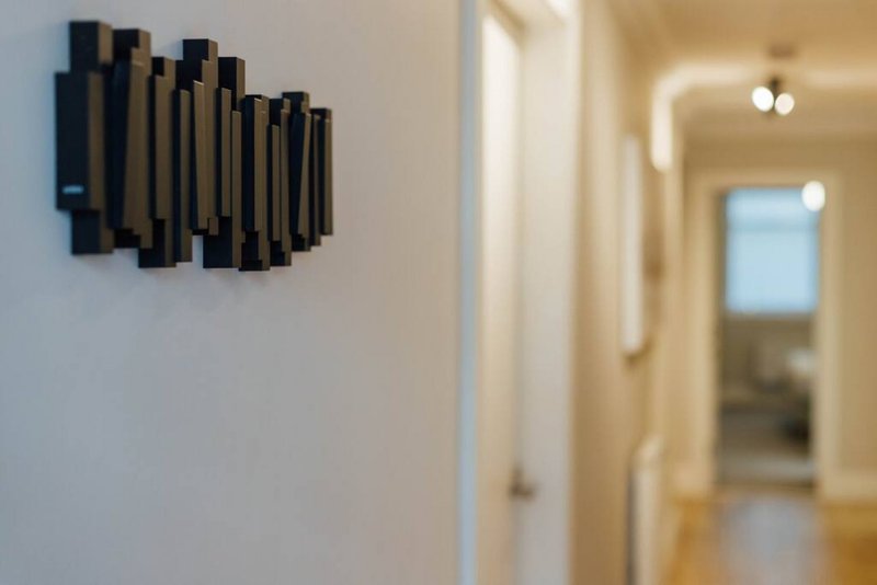 Hallway with white walls, black abstract wall art, and doorway to adjacent room