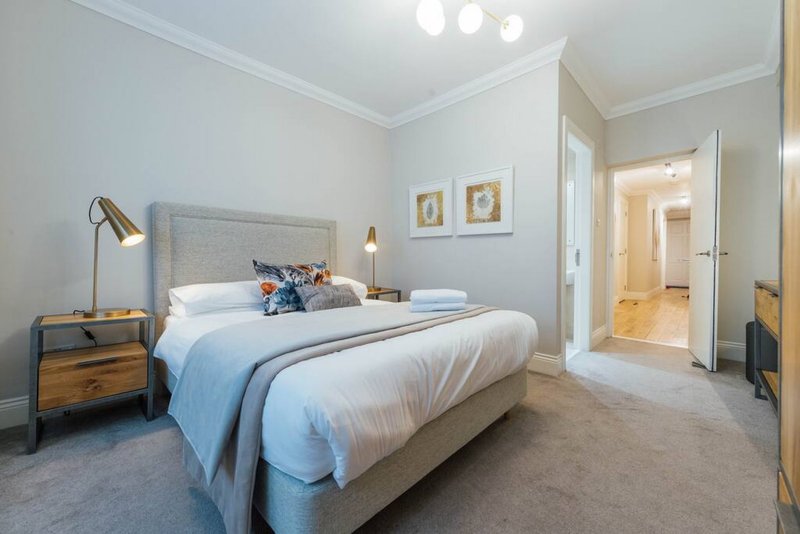 Modern bedroom with double bed, blue throw, wooden nightstand and brass lamp