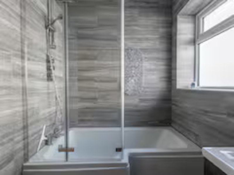 Modern bathroom with walk-in shower, gray tile walls, white window and white bath tub