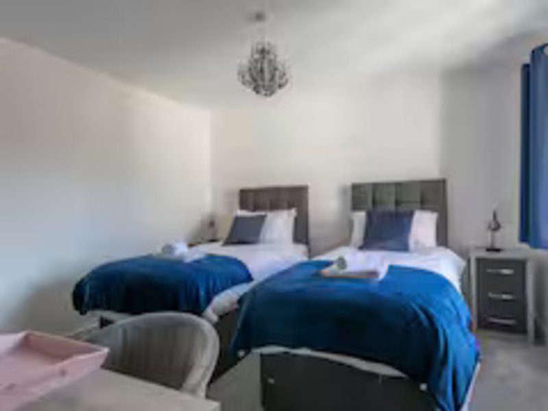 Twin bedroom with blue duvets, upholstered headboards, bedside tables and chandelier