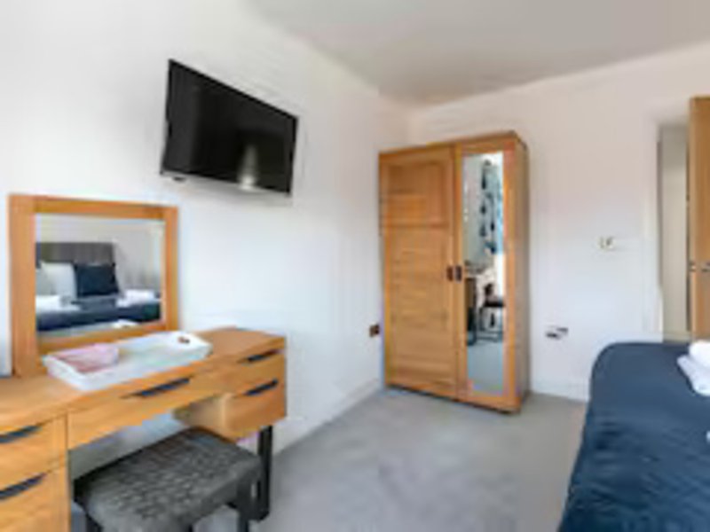 Bedroom with two beds, wooden furniture, wall-mounted TV, and mirror