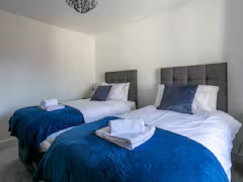 Twin bedroom with two beds, blue throws, white pillows and bedside tables