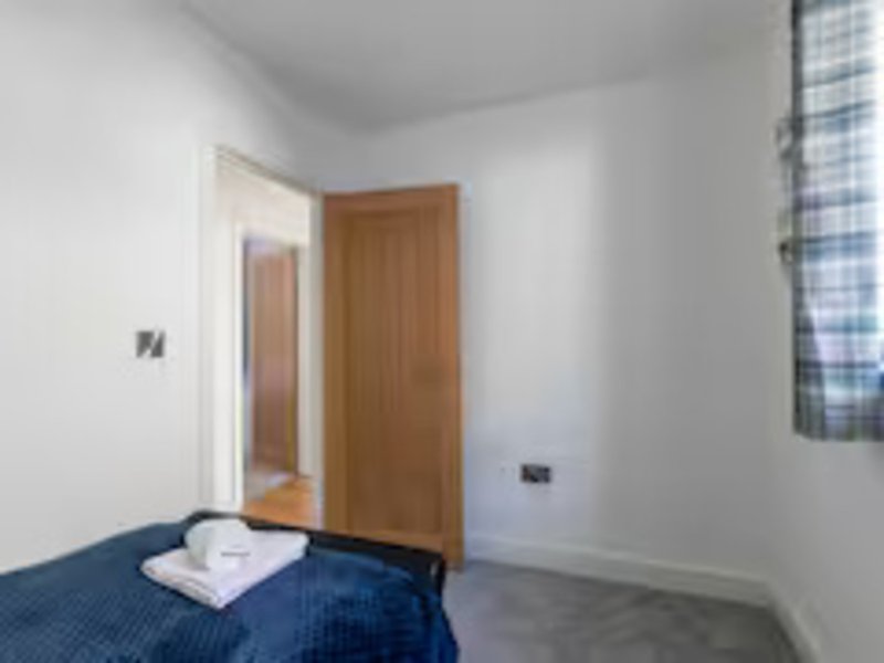 Bedroom with single bed, wooden door, white walls and small window
