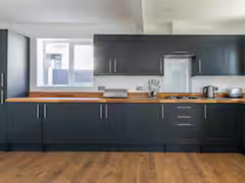 Modern kitchen with dark cabinetry, wood countertop, stainless steel appliances and window