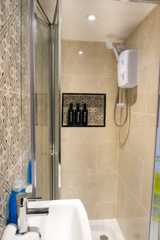 Modern bathroom with walk-in shower, beige tiles, white sink and chrome fixtures