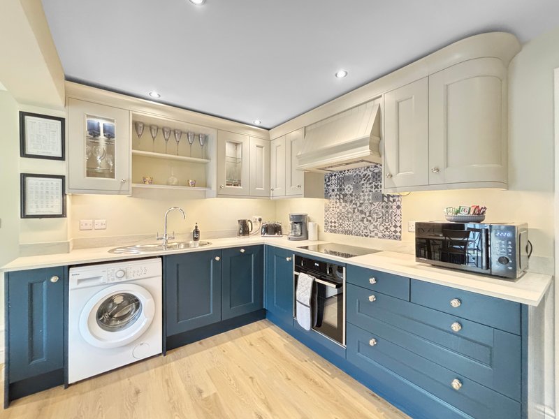 Modern kitchen with blue and cream cabinetry, white washing machine, and mosaic backsplash