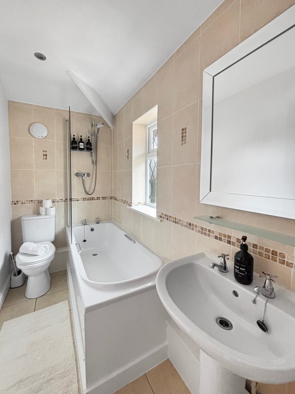 Bathroom with bathtub, pedestal sink, toilet, mirror and shower enclosure