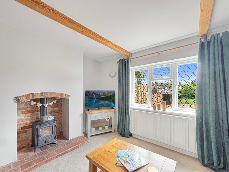 Bright living room with exposed beam, fireplace, wood table and leaded windows