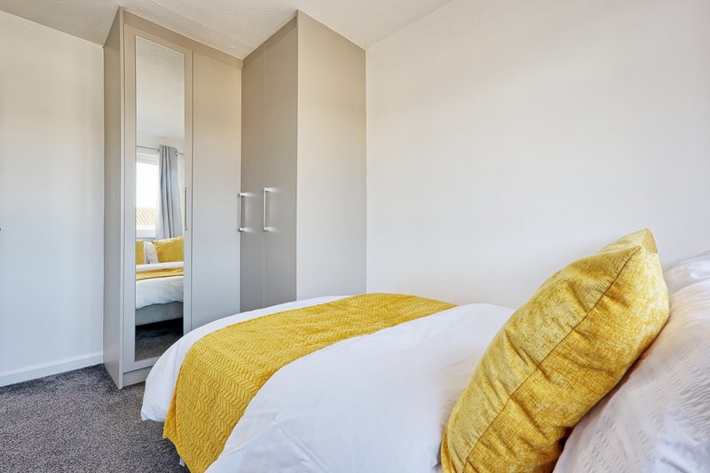 Bedroom with double bed, yellow cushions and throw, built-in wardrobe with mirror