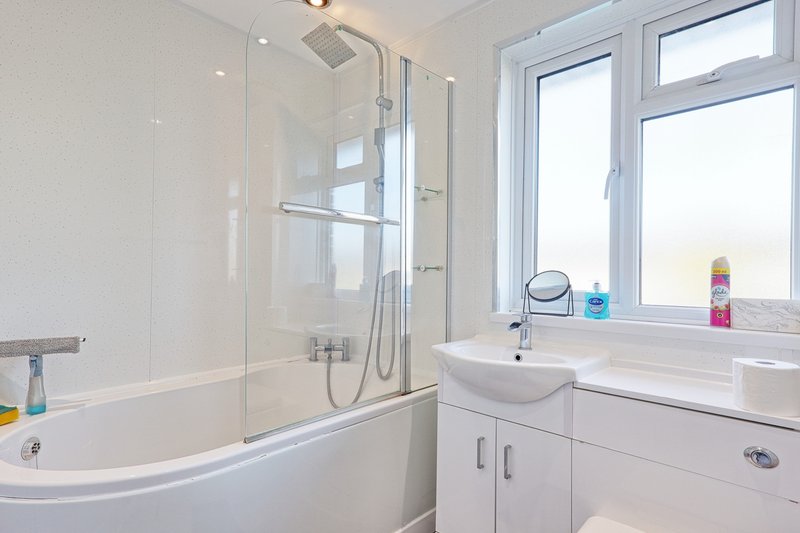 Modern bathroom with white suite, glass shower enclosure, sink and mirror