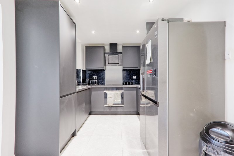 Modern galley kitchen with gray cabinetry, white countertops, and stainless steel appliances