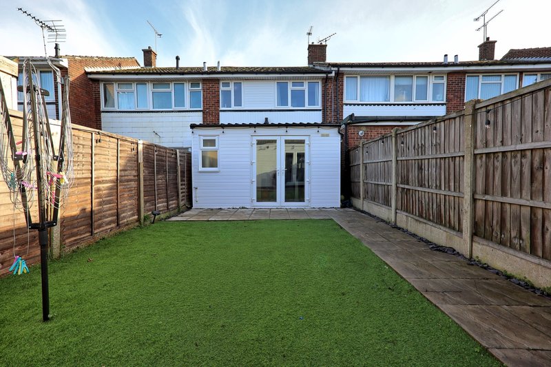 Rear garden with lawn, wooden fencing, and modern extension with glass doors