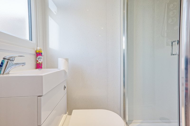 Modern bathroom with white vanity, toilet, shower enclosure and window