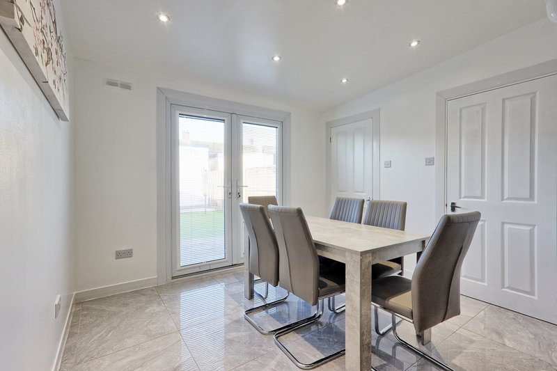 Modern dining room with table, four chairs, glass doors to garden, recessed lighting