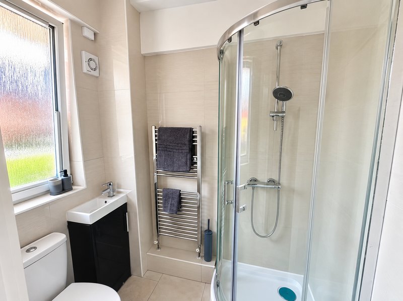 Modern bathroom with shower enclosure, toilet, sink vanity, and heated towel rail