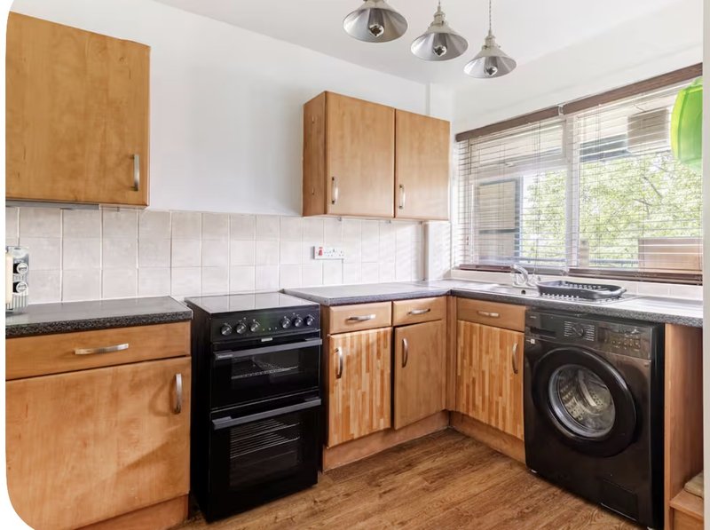 Kitchen with wooden cabinets, black appliances, white tile backsplash and windows