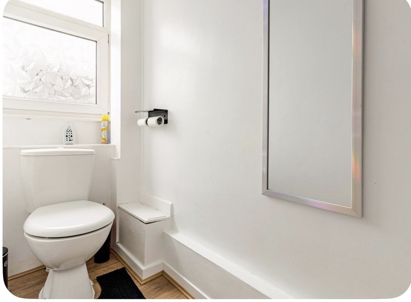Compact bathroom with toilet, sink, mirror and small window