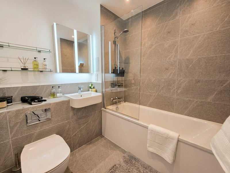 Modern bathroom with toilet, sink, illuminated mirror, bathtub and walk-in shower