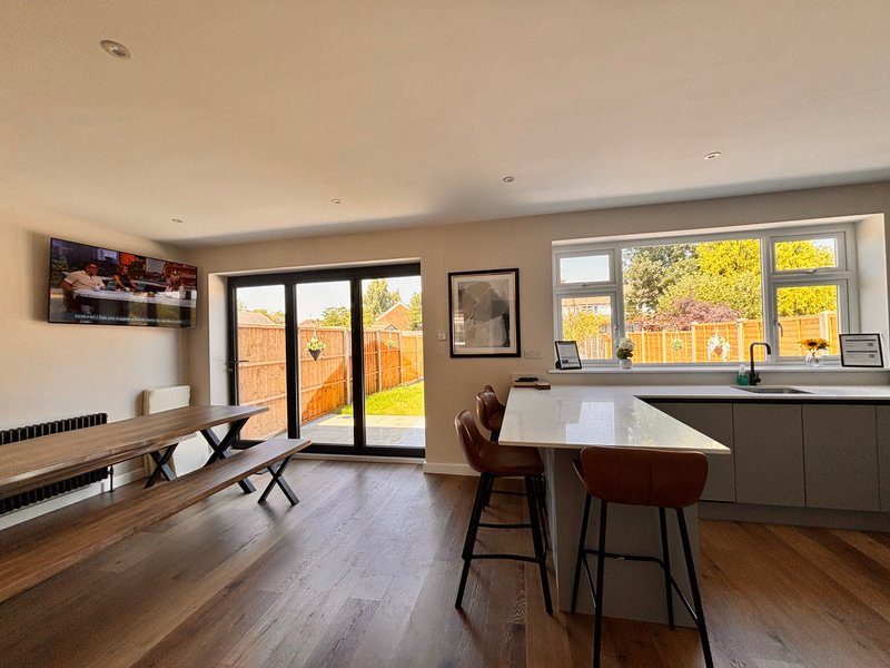 Open-plan kitchen and dining area with wooden flooring, island seating, and garden views