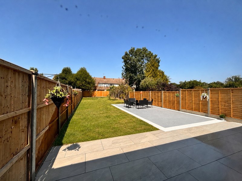 Garden with paved patio, lawn, wooden fences and distant house views